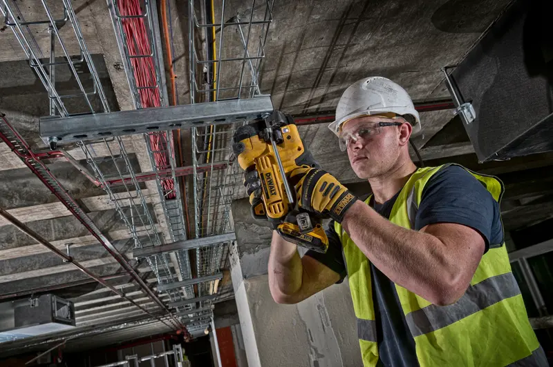 Ouvrier utilisant DEWALT DCS350NT pour couper une conduite métallique au plafond.