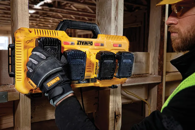 Photo du chargeur DEWALT DCB104 à quatre ports fixé sur bois, batteries connectées, chantier.